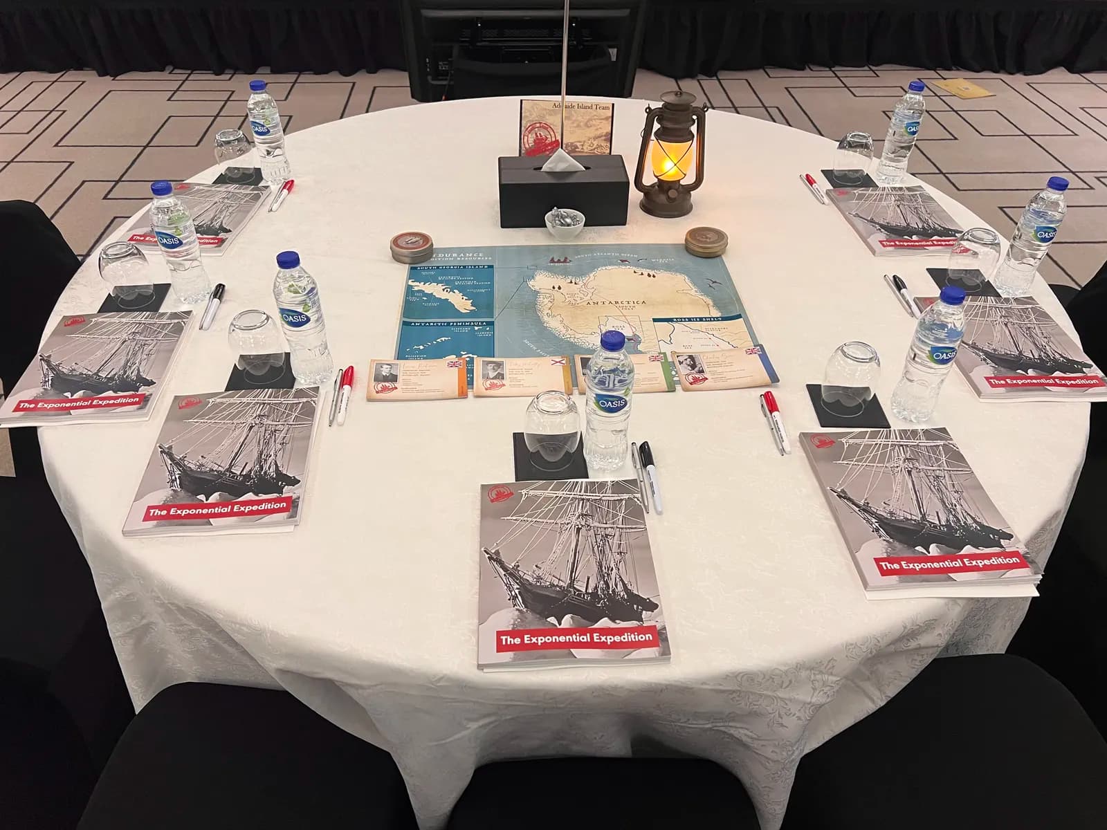 Lead the Endurance table close-up — Shackleton expedition workbooks, an Antarctica map, and a lantern set for leaders to work the strategy